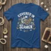 Covered In Seamen text with illustrations of sailors, anchors, and a ship's wheel on a blue t-shirt