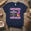 Cupcakes Are Muffins That Believed In Miracles quote on a navy t-shirt with a pink cupcake graphic