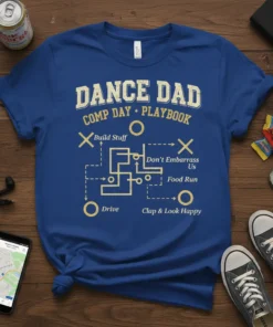 Blue t-shirt with yellow text "DANCE DAD COMP DAY PLAYBOOK" and a dance competition playbook diagram with terms like "Build