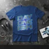Day One Ish text graphic on a blue t-shirt, featuring metallic silver letters with blue neon accents and digital circuit