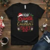 Black t-shirt with "Dear Santa It's My Coworker's Fault" text in festive red and gold, featuring Santa hat and Christmas
