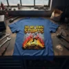 Do My Own Stunts t-shirt featuring a mummy-like figure on crutches amidst flames and tires