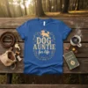 Blue t-shirt with "DOG AUNTIE fur life" text and a golden retriever graphic, set against a forest background