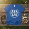Blue t-shirt with white "Dog Mom Bod" text and a paw print graphic, surrounded by a laurel wreath design