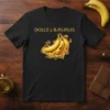 Dolce & Bananas text above a glowing bunch of bananas with ornate swirls on a black t-shirt