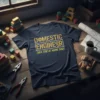 Navy t-shirt with "DOMESTIC ENGINEER (AKA STAY AT HOME DAD)" text in distressed gold and white font, featuring gear graphics