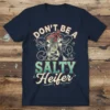 DON'T BE A SALTY Heifer text with a cow wearing a bandana graphic on a navy t-shirt