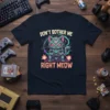 Don't Bother Me Right Meow text with a robotic cat holding a game controller on a navy t-shirt