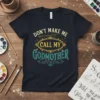 Don't Make Me Call My Godmother text design with a magic wand and decorative elements on a navy t-shirt