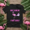 Black t-shirt with pink text "DON'T SCARE ME I FART EASILY" and a graphic of a flamingo with colorful smoke