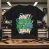 Black t-shirt with "DON'T TOUCH MY HAIR BRUH" text in colorful graffiti style, featuring scissors and comb graphics