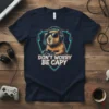 Don't Worry Be Capy humorous quote t-shirt featuring a capybara wearing headphones and sunglasses, playing a video game