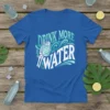Blue t-shirt with "DRINK MORE WATER" text in stylized blue and white lettering, featuring a hand holding a glass of