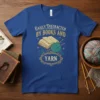 Easily Distracted By Books And Yarn text with an open book and teal yarn on a royal blue t-shirt