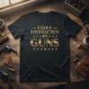 Black t-shirt with gold text "EASILY DISTRACTED BY GUNS" and star accents, featuring vintage revolvers and ammo on a wooden