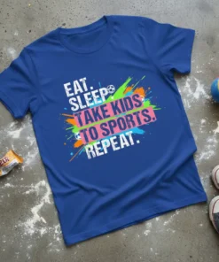 Blue t-shirt with white text "EAT. SLEEP. TAKE KIDS TO SPORTS. REPEAT." and colorful paint splatters, including soccer balls