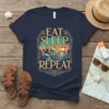 Eat Sleep Yeet Repeat t-shirt with colorful retro beach sunset design and waves, navy blue tee