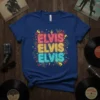 Blue t-shirt with "ELVIS ELVIS ELVIS" in stacked neon lettering in pink, yellow, and teal, surrounded by colorful stars and