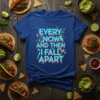 T-shirt with the quote "EVERY NOW AND THEN I FALL APART" in bold, fragmented blue and orange lettering