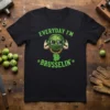 T-shirt with "Everyday I'm Brusselsin'" text and a cartoon Brussels sprout wearing sunglasses and headphones, holding Bitcoin symbol