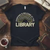 Everyone Is Welcome At The Library text with a gold rainbow graphic on a black t-shirt