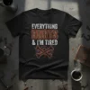 Black t-shirt with white and orange text reading "EVERYTHING HURTS & I'M TIRED" above crossed bones and gears graphic