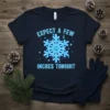 Expect A Few Inches Tonight humorous snowflake graphic t-shirt, featuring a smiling blue snowflake and playful text