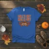Blue t-shirt with orange text "FALL'S OUT BALL'S OUT" and an acorn graphic with autumn leaves