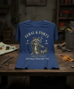 Feral & Forty Still Digging Through Life's Trash T-Shirt with a smoking raccoon graphic and vintage style