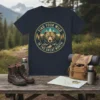 Find Your Wild In The Great North text with a bear graphic, mountains, and trees on a navy blue t-shirt