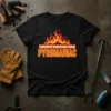 Black t-shirt with bold orange and yellow text "FIREPIT MASTER AKA PYROMANIAC" above a graphic of flames
