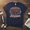 Fueled by Chemo & Sarcasm text design on a navy blue t-shirt with wings and gears graphic elements