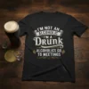 Black t-shirt with white and gold text: "I'm Not an Alcoholic I'm a Drunk Alcoholics Go to Meetings" quote design