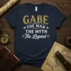Navy t-shirt with "Gabe The Man The Myth The Legend" text in distressed gold and white font, featuring knight shield
