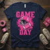 Navy blue t-shirt with bold pink "GAME DAY" text, a pink football helmet, and a pink football with ribbons