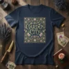Garden City text in a decorative floral border, featuring birds and botanical elements on a navy blue t-shirt
