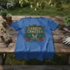 Garden Gangsta T-Shirt featuring bold gold text, scissors, cannabis leaf, and strawberries, with Monstera leaves and roses