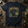 Black cat wearing a floral wreath with the text "GARDENING BECAUSE MURDER IS WRONG" on a navy t-shirt