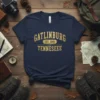 Navy blue t-shirt with "GATLINBURG EST. 1945 TENNESEEE" in distressed gold font, vintage travel design