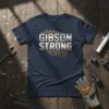 Navy blue t-shirt with "Gibson Strong" text in metallic silver and industrial gears graphic