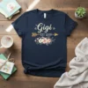 Navy blue t-shirt with "Gigi EST 2019" text, floral graphics, and golden arrow design