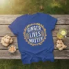 Ginger Lives Matter slogan in distressed circle graphic on a royal blue t-shirt, with ginger roots and drink nearby