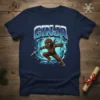Ginja Gingerbread Ninja T-Shirt with a brown gingerbread man in ninja attire holding a candy cane sword and shuriken, surrounded