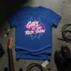 Blue t-shirt with "GIRL AT THE ROCK SHOW" in neon pink and yellow lettering, set against a vibrant graphic background