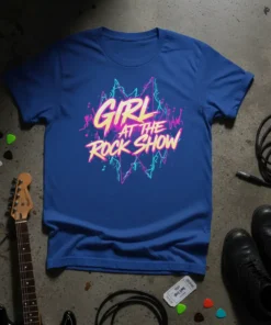 Blue t-shirt with "GIRL AT THE ROCK SHOW" in neon pink and yellow lettering, set against a vibrant graphic background