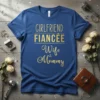 Girlfriend Fiancée Wife & Mommy text design on a royal blue t-shirt, with gold glitter font
