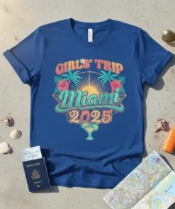 Girls' Trip Miami 2025 text graphic with palm trees, hibiscus flowers, and a sunset design on a blue t-shirt