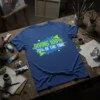Blue t-shirt with bold green and blue text reading "GIVING 100% 70% OF THE TIME" in a distressed paint splash