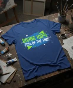Blue t-shirt with bold green and blue text reading "GIVING 100% 70% OF THE TIME" in a distressed paint splash
