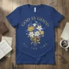 Blue t-shirt with gold text "GOD IS GOOD ALL THE TIME" and a floral bouquet design